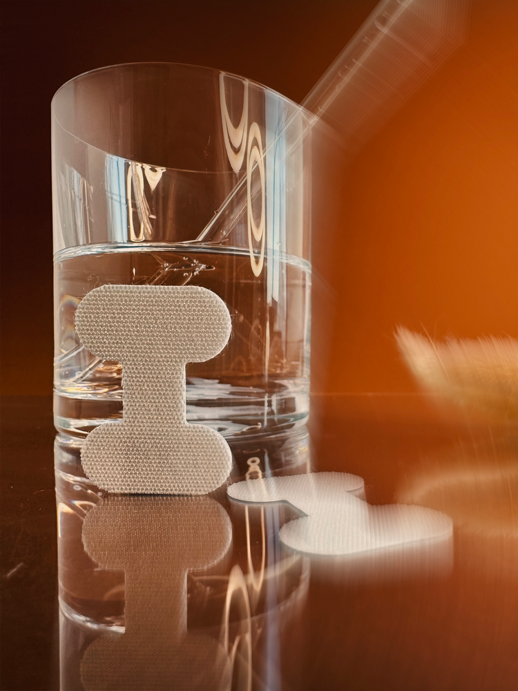 Tape Nahaufnahme angelehnt an ein Glas mit Wasser drin und einem braunem Hintergrund - Mouth Taping und Nachts trinken